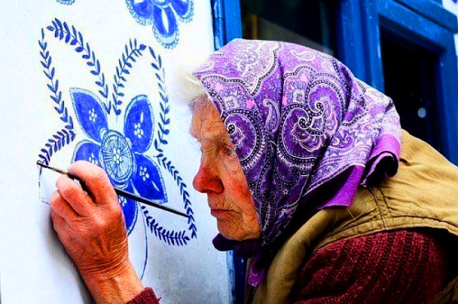 סבתא צ’כית בת 93, מעטרת בפרחים מצוירים את בתי שכניה בכפר