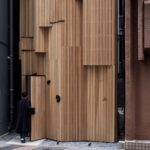 מסעדה קומפקטית מעץ נדחקה במרווח צר בין בתי טוקיו